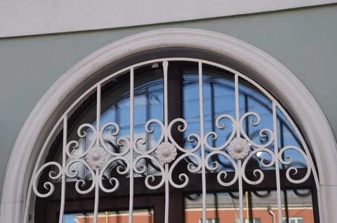 A window with an arch and an openwork white lattice on the wall of a buildi.. Foto stock