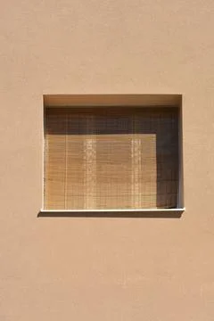 Window with a bamboo roller blind on a beige facade Stock Photos