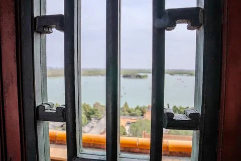 Window bars framing lake view from historic building Stock Photos