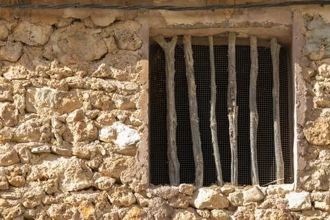 A window with bars on it is shown in a stone building Stock Photos