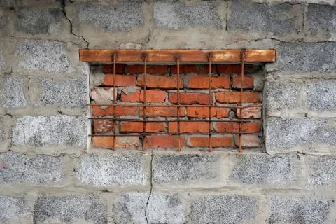The window on the basement is covered with red bricks and a grille is install Stock Photos