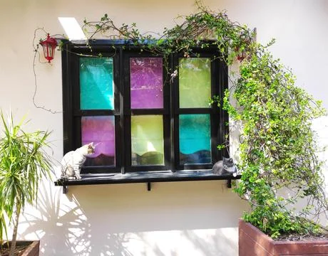 A window in a black frame with multicolored glass on the facade Stock Photos