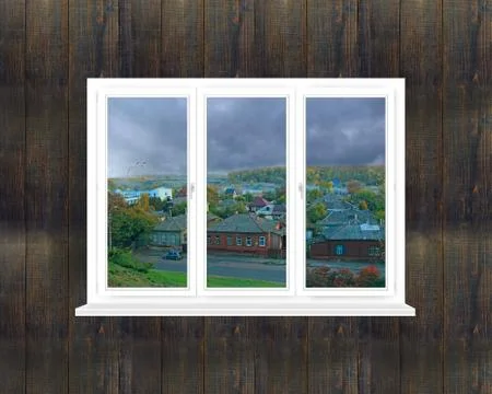 Window on black wall overlooking cloudy landscape in village Foto stock