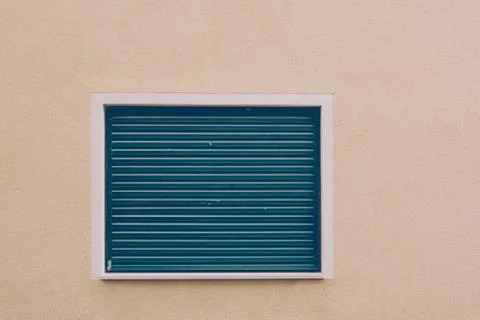 Window with blue roller shutter on smooth brown wall Stock Photos