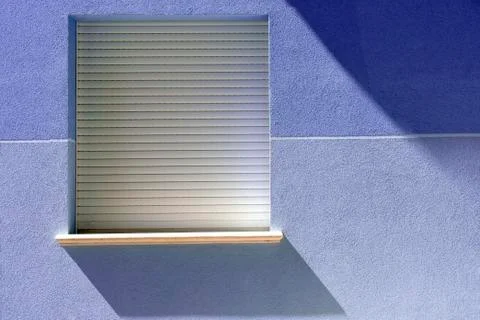 Window on blue wall with geometric shadow from the sun. Stock-Fotos