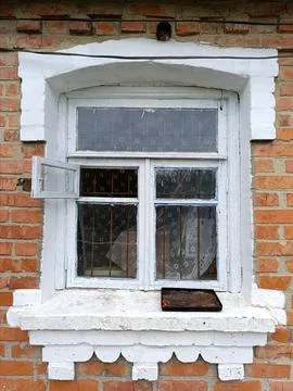A window on a brick building with a white frame and a window sill Stock Photos
