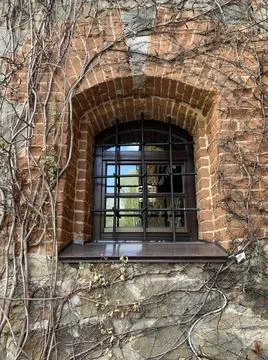 Window in the brick wall of the castle. Window opening in a medieval building Stock Photos