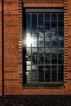 Window in brick wall with reflection of the container port of Hamburg Stock Photos