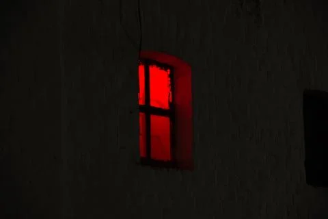 Window with burning red light in the night dark Stock Photos