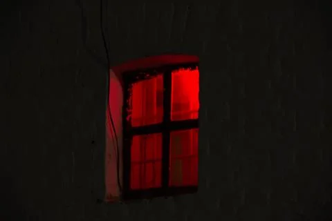 Window with burning red light in the night dark Stock Photos
