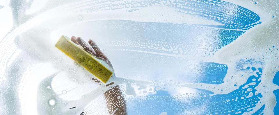 Window cleaner cleaning window with squeegee and wiper on a sunny day Stock Photos
