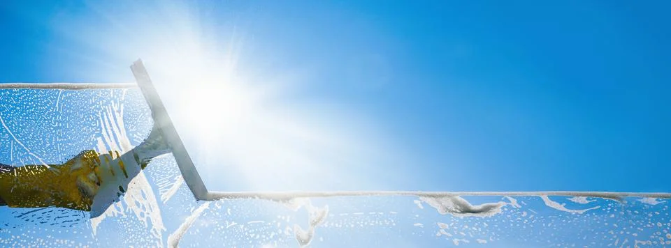 Window cleaner cleaning window with squeegee and wiper on a sunny day with a  Stock Photos