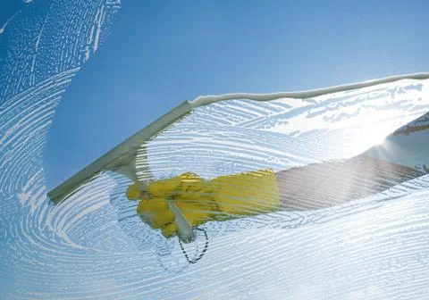 Window cleaner cleaning window with squeegee and wiper on a sunny day Foto stock