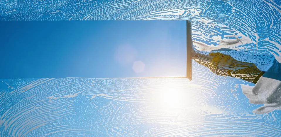 Window cleaner cleaning window with squeegee and wiper on a sunny day with a  Stock Photos