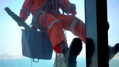 Window cleaner climber climbing up the window of a building shot from inside Stock Footage 225125189