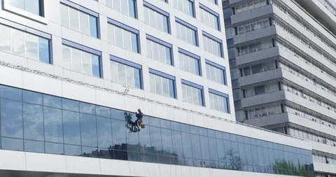 Window cleaner with the equipment washes the Windows of the business center Stock Footage 90580000