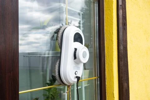 A window cleaner robot cleans windows in a house from the outside. Cleaning.. Stock Photos