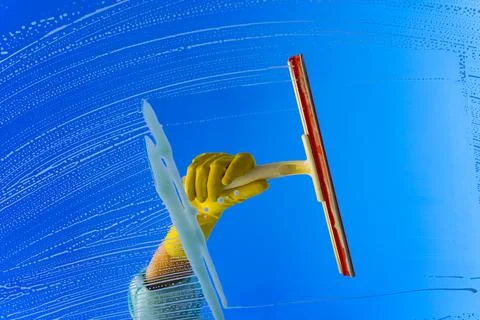 Window cleaner using a squeegee or wiper to wash a window glass Stock Photos