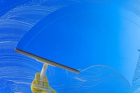 Window cleaner using a squeegee or wiper to wash a window glass. Copy space Stock Photos