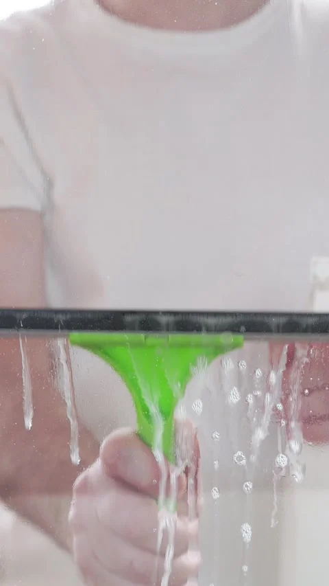Window cleaner using a squeegee to wash a window Stock-Footage 304870296