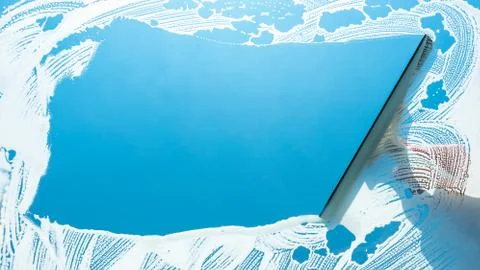 Window cleaner using a squeegee to wash a window Stock-Fotos