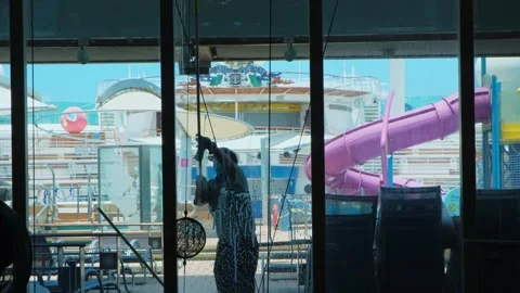 Window cleaner, wearing protective mask and using hand wiper, washes glass in Stock-Footage 274485467