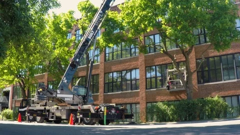 Window cleaner working on a building from a crane Stock Footage 92147816