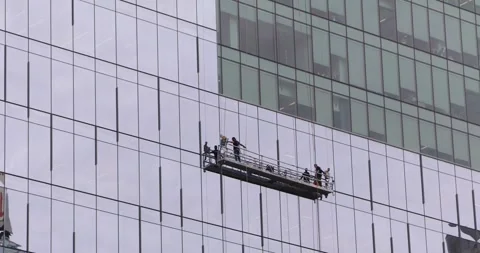 Window cleaners on suspended platform working on glass office tower Stock Footage 321035642