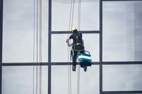Window cleaners at work. Window cleaner, in the suspension system. Industrial Stock Photos