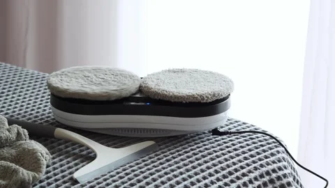 Window cleaning robot with dual microfiber pads, resting on a textured surface,  Stock Footage 313883645