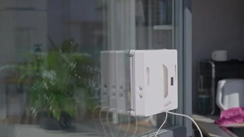Window cleaning robot moves on window with visible water spray and splashes Stock Footage 330434419