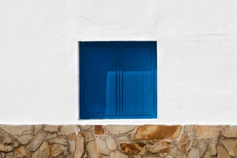 A window with closed blue shutters in white wall Stock Photos
