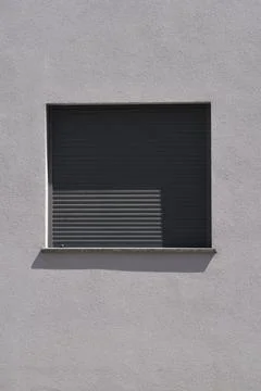 Window with closed grey roller shutter on a concrete wall Stock Photos