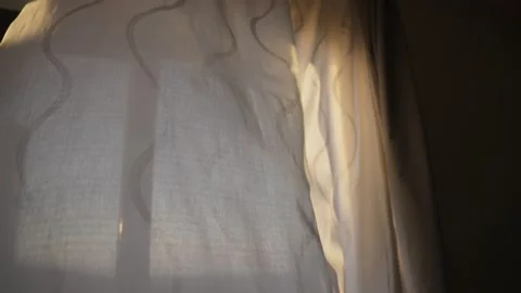 Window curtain or blind is blowing in the wind as sun shines through it Stock Footage 220514729