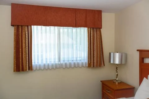 Window with the curtains and bedside table in the corner of the room Stock Photos