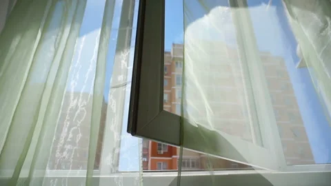 Window with curtains and a view of the sky and city. Conceptual story of the Stock Footage 93651147