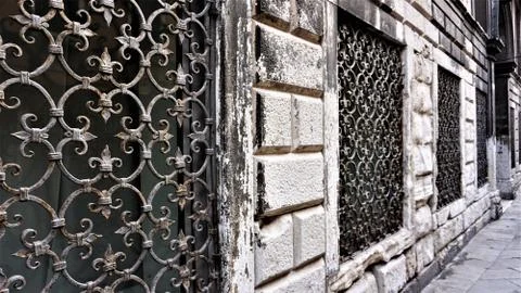 Window with a decorative metal grid of old Venetian times on the wall of an o Stock Photos