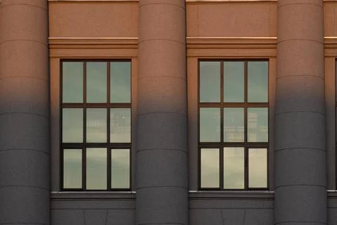 The window detail of the library framed by three collumns, split by the sunse Stock Photos