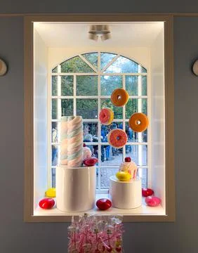 A window display features colorful donuts, a cupcake, and a marshmallow Stock Photos