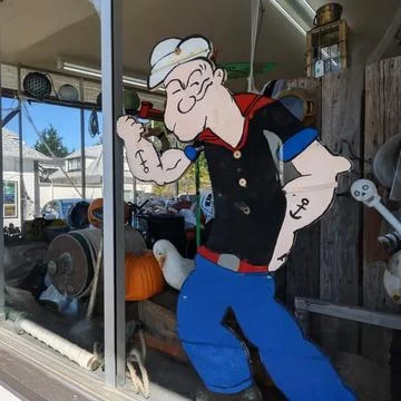A window display featuring a life-size cardboard cutout of “Popeye” Stock Photos