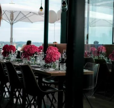 Window of an empty restaurant with glasses and cutlery and a vase of flower. Stock-Fotos