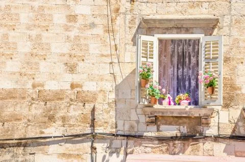 Window with flowers on the background of a white stone wall typical of Stock Photos