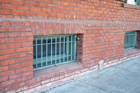 Window grade blocking lower floors of a brick warehouse building on sidewalk Foto stock