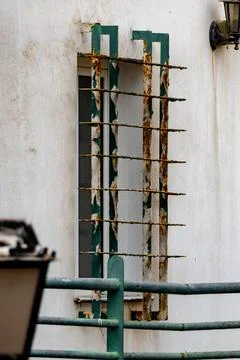 A window with a green frame and a rusty metal bar Stock Photos