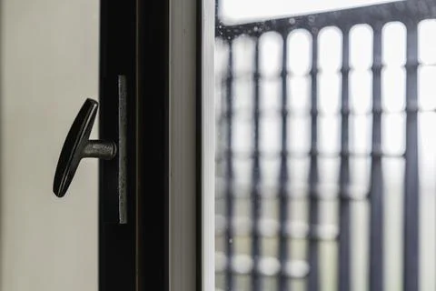 Window handle and blurred railing on balcony looking outside Photos