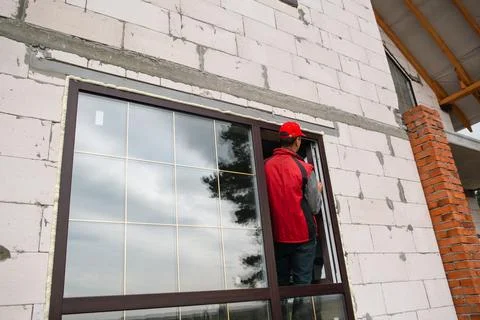 Window installer works on PVC frame placement in new house, accurate alignm.. Stock Photos