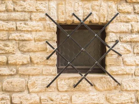 Window with iron grating on a stone wall. Stock Photos