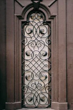 A window with a metal grille with patterns with a lilac sheen. Fotos de archivo