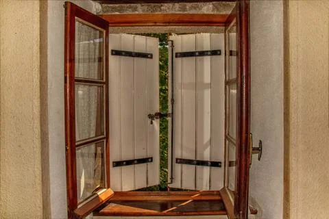 Window in an old rustic stone house with openwork curtains and white closed s Stock Photos