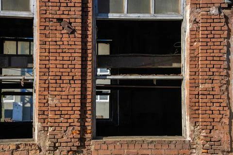 Window openings with dismantled windows in an old brick factory building Stock Photos